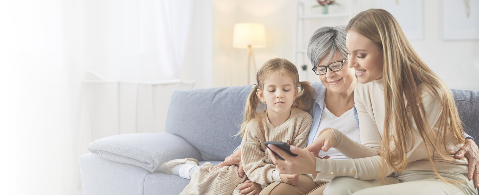 Three generations of a family sitting together looking at a phone